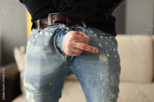 Man showing middle finger from fly of jeans close-up. Potency problems concept photo