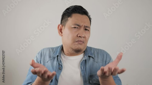 Young Asian man with shrug shoulder up gesture, showing i don't know or rejection