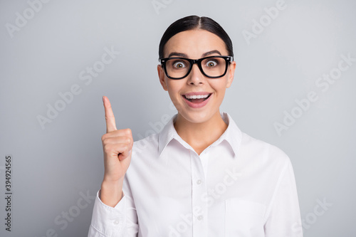 Photo of funny smart young lady raise finger have idea wear white shirt isolated grey color background
