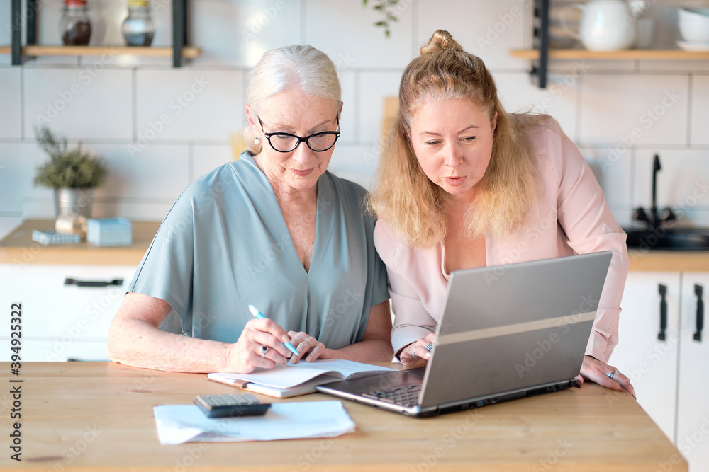 daughter helps her elderly mother figure it out online with her personal account. Woman teaching senior mother to use internet at home. Senior woman with her daughter looking at modern gadget indoors. daughter helps her elderly mother figure it out online with her personal account. Woman teaching senior mother to use internet at home. Senior woman with her daughter looking at modern gadget indoors.