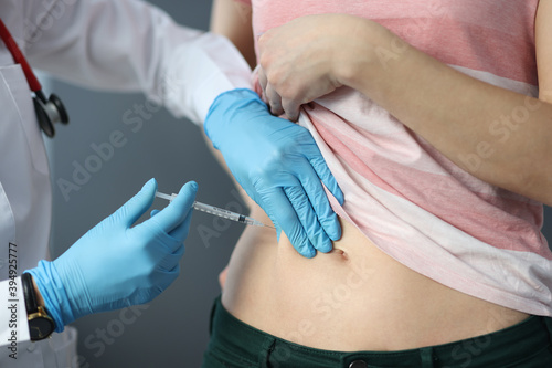 Doctor in rubber gloves making injection into patients skin fold close-up. Diabetes treatment concept