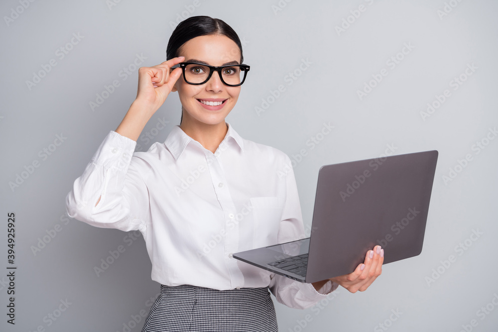 Photo of charming confident girl hold netbook adjust eyewear wear spectacles white shirt isolated grey color background Photo of charming confident girl hold netbook adjust eyewear wear spectacles white shirt isolated grey color background