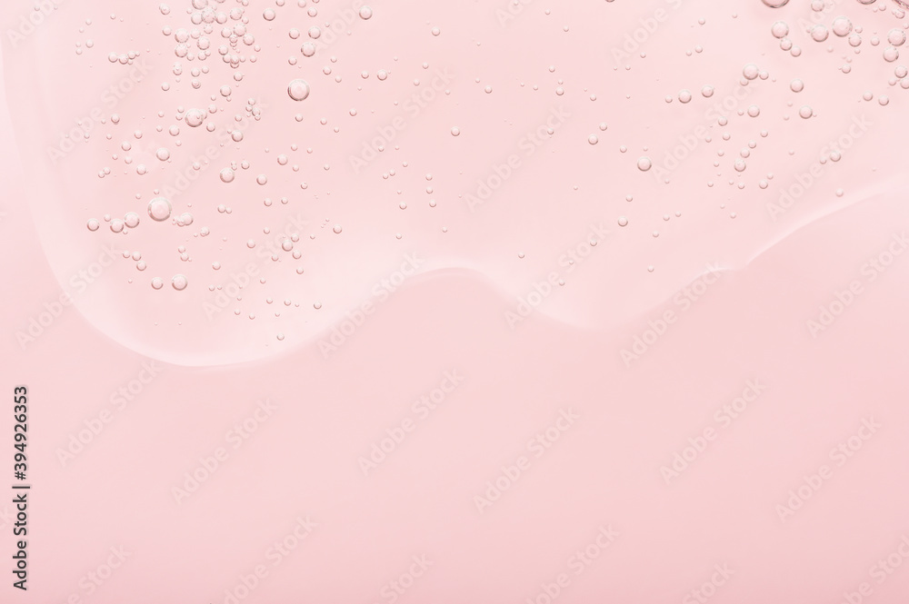The texture of the gel, skincare serum on a pink background. A transparent liquid cosmetic with bubbles to moisturize the skin of the face and body. Cleansing beauty product, scrub with natural acids