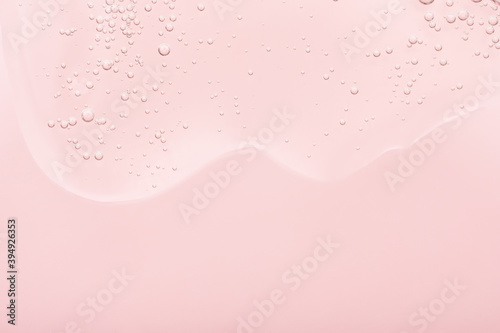 Obraz na płótnie The texture of the gel, skincare serum on a pink background. A transparent liquid cosmetic with bubbles to moisturize the skin of the face and body. Cleansing beauty product, scrub with natural acids w salonie