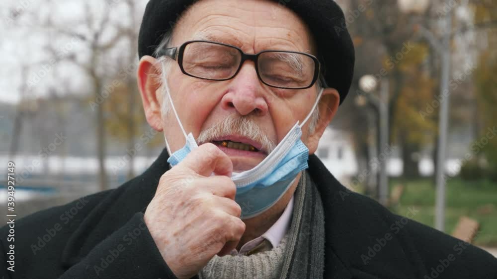 elderly man takes off medical mask. Breathes deeply and smiling looking at camera on blurred background. Health care and medical concept. Safety life,COVID19 coronavirus,healing virus,stop pandemi