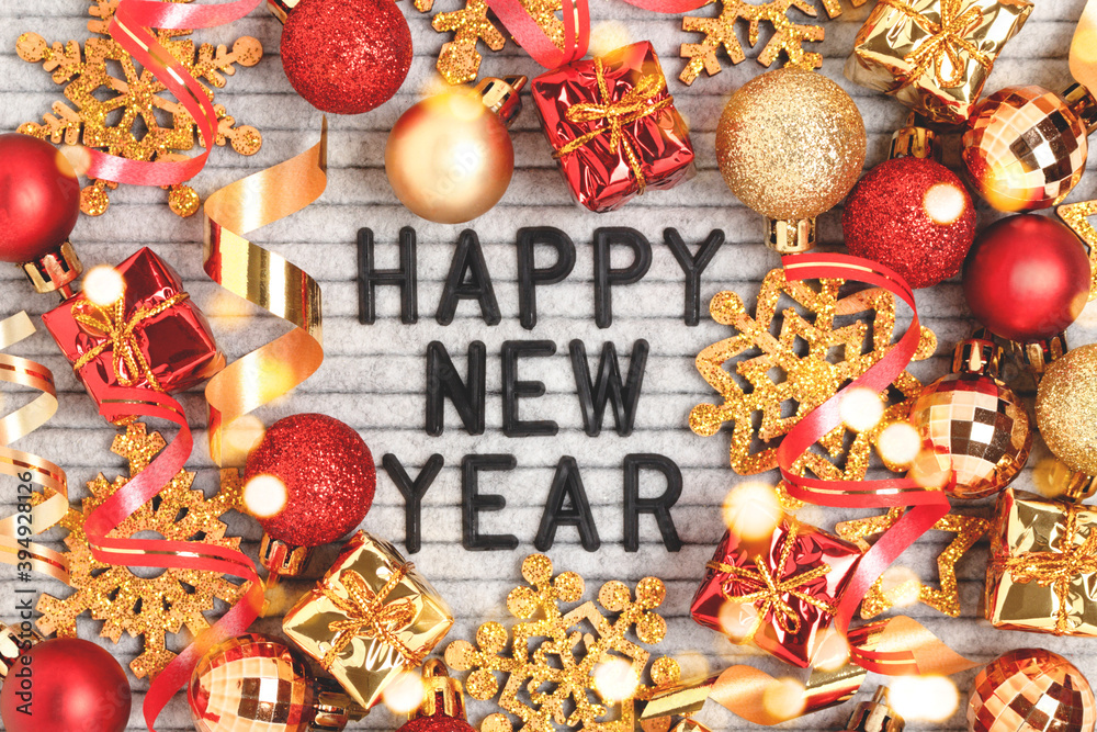 Fototapeta premium Happy New Year - quote on a felt letter board. Christmas concept with red and gold festive decorations.