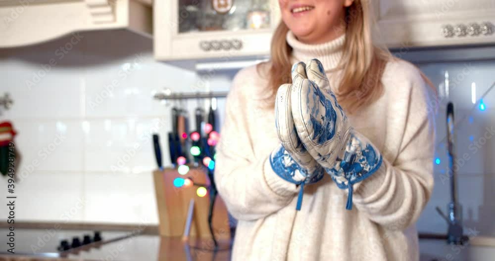 Close up shot of pretty girl claps potholders and laughing in slow motion. Celebrating new year and christmas 2021 at home during covid-19 coronavirus pandemic quarantine concept.