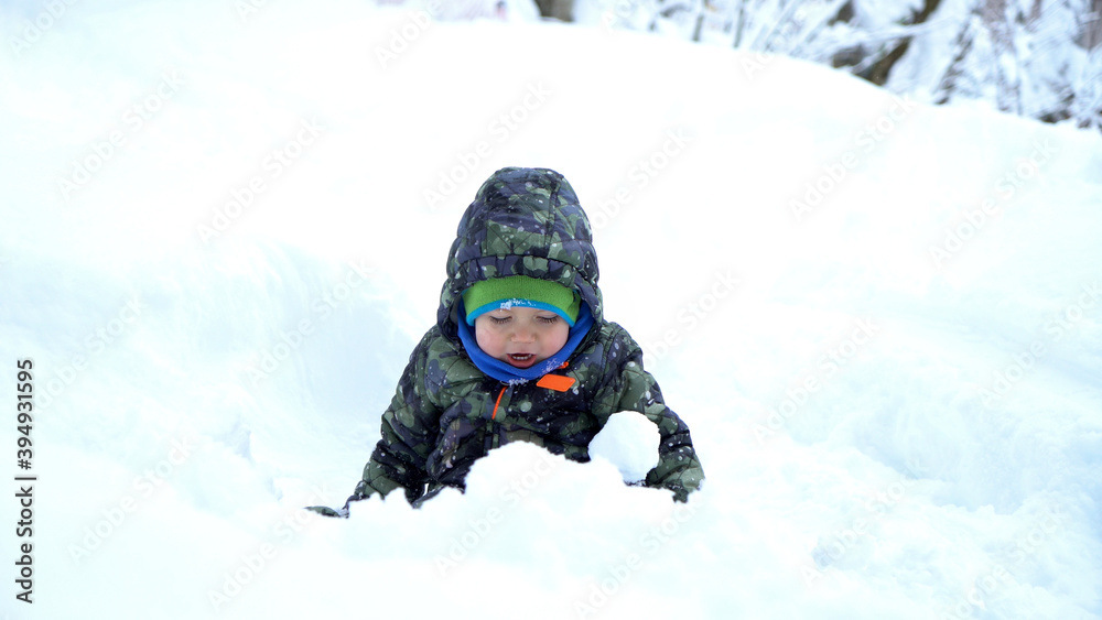 Baby boy playing snowballs at snowy winter day