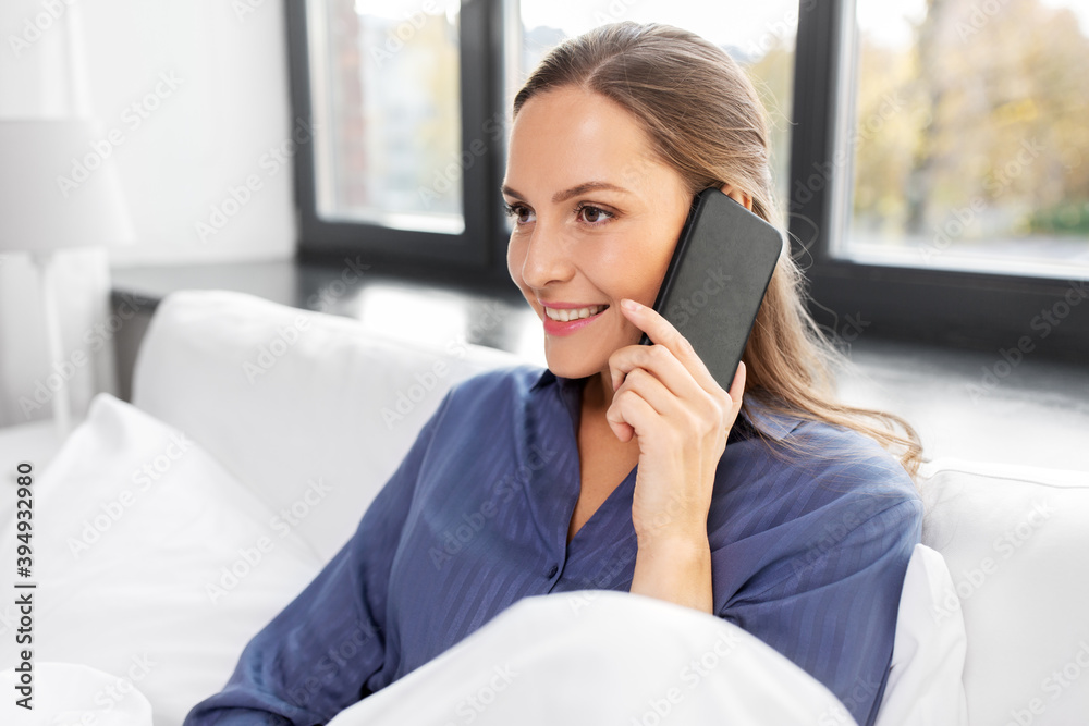 people, bedtime and rest concept - happy smiling woman calling on smartphone in bed at home people, bedtime and rest concept - happy smiling woman calling on smartphone in bed at home