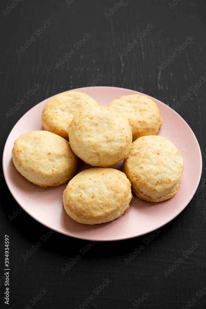 Homemade Flaky Buttermilk Biscuits on a pink plate on a black background, low angle view. Homemade Flaky Buttermilk Biscuits on a pink plate on a black background, low angle view.