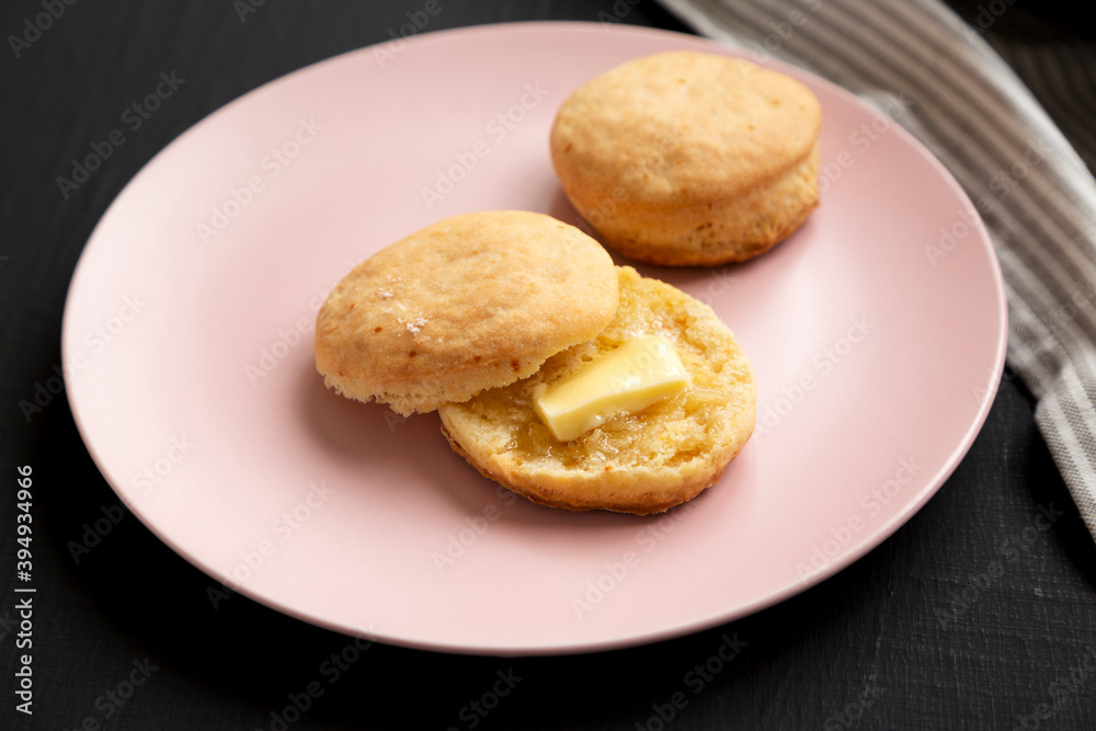 Homemade Flaky Buttermilk Biscuit on a pink plate on a black surface, low angle view. Close-up.