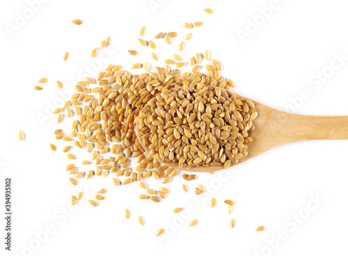 Golden linseed, linen seeds with wooden spoon isolated on white background, top view