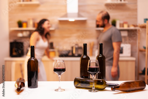 Couple having romantic night in kitchen with red wine after getting married.