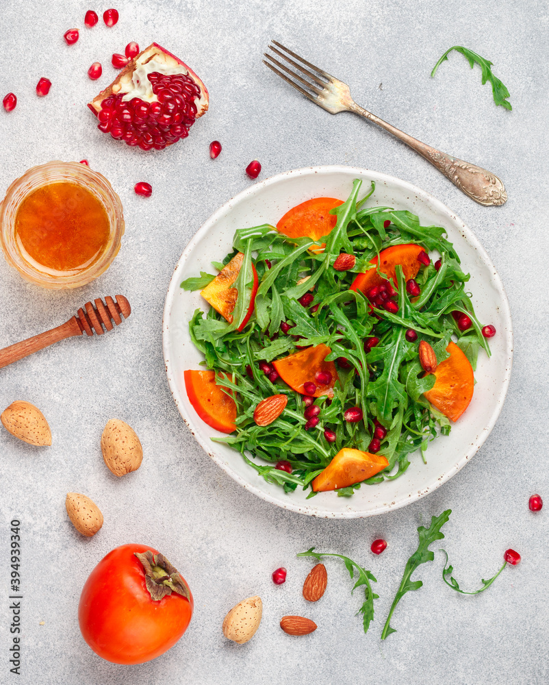 Φωτογραφία Delicious salad of fresh arugula, persimmon, pomegranate and almonds with a dressing of olive oil and honey