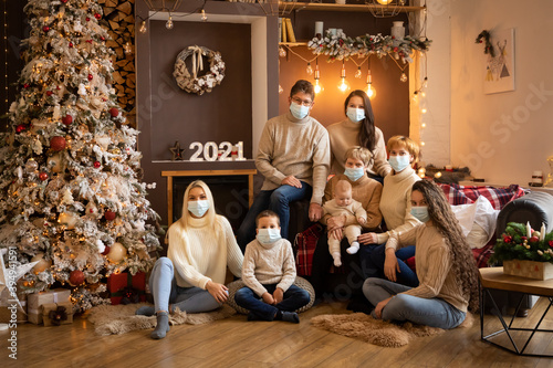 Multi Generation Family in protective face masksnear Christmas tree in modern decorated home, Happy New year 2021