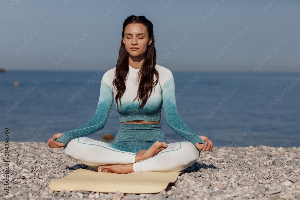 Caucasian young woman practicing yoga at seashore