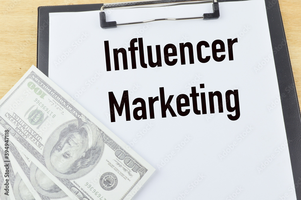 Top angle view of banknotes and paper holding file written with text INFLUENCER MARKETING. Business concept. Top angle view of banknotes and paper holding file written with text INFLUENCER MARKETING. Business concept.