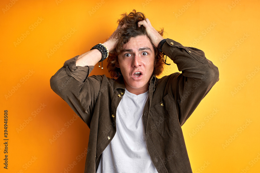 annoyed man in shock, touching head at a loss, look at camera, isolated orange background annoyed man in shock, touching head at a loss, look at camera, isolated orange background