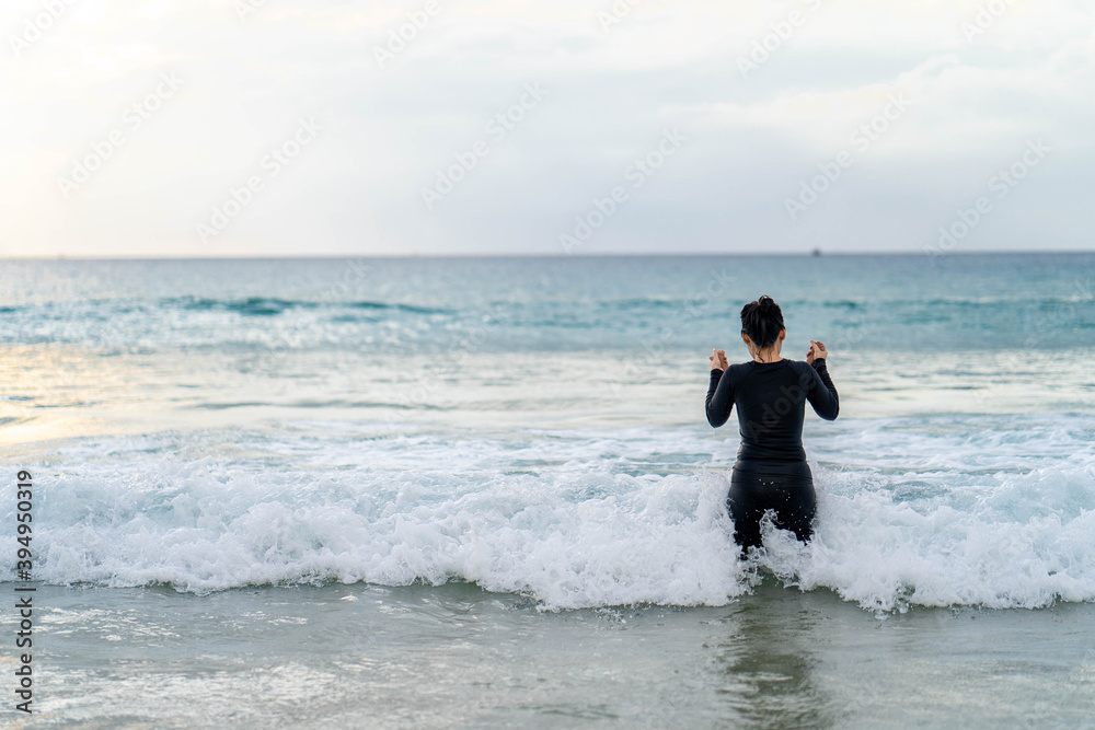 Active young mother and daughter in swimming suit playing at the beach 