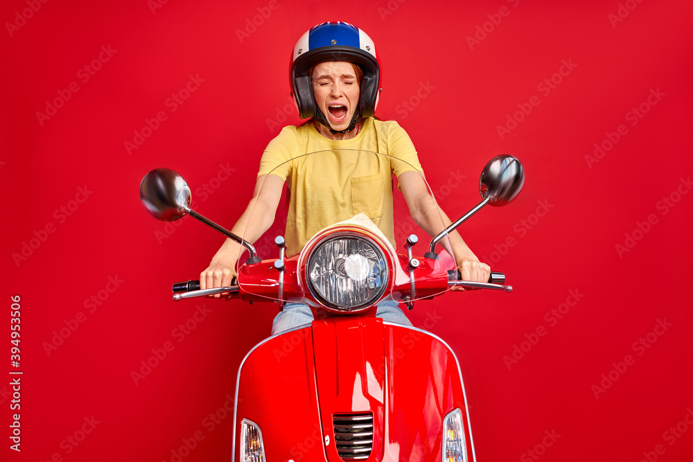 young caucasian woman on motorcycle had an accident on a road, she is scared, sits in casual wear and protective helmet, saved her life