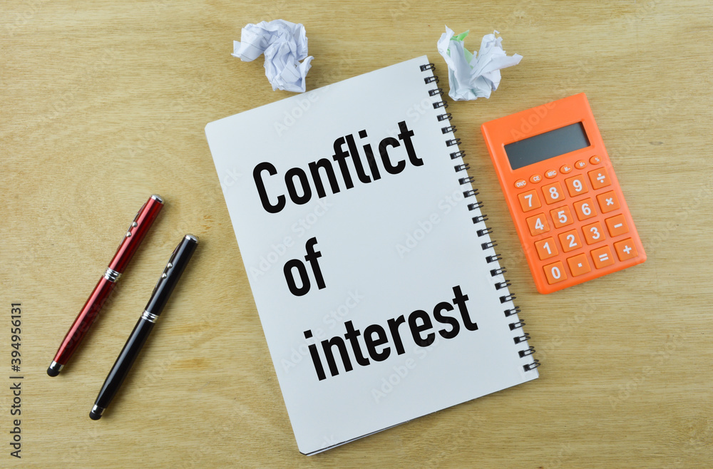 Selective focus of calculator, paper waste, pens and notebook written with text CONFLICT OF INTEREST. Selective focus of calculator, paper waste, pens and notebook written with text CONFLICT OF INTEREST.