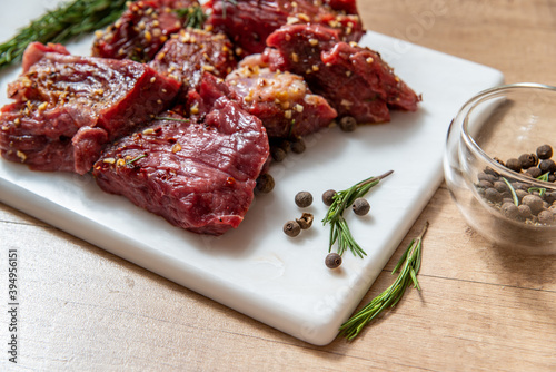 raw lamb chops with rosemary and pepper on marble board. preparing meat. marinated meat. beef. preparing food on kitchen. cooking. beef steak with vegetables