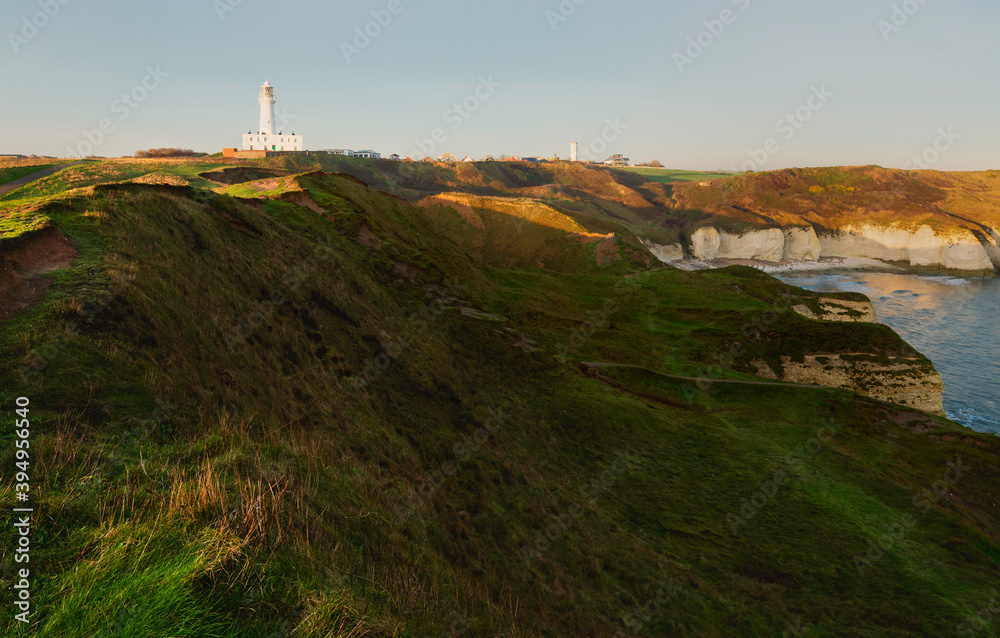 View across English coastline towards lighthouse at sunrise. Flamborough, UK.