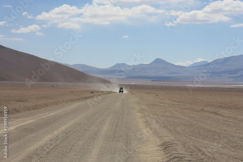 car driving on desert road between mountains in the altiplano in Bolivia