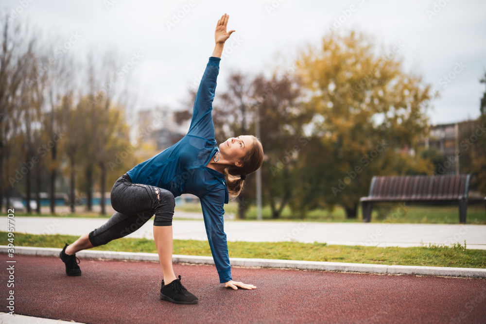 Beautiful adult woman is exercising outdoor on cloudy day in autumn. - obrazy, fototapety, plakaty 