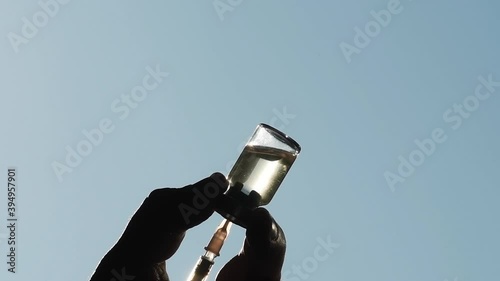 Close up of a medical vial and a syringe filled with vaccine. Silhouette against blue background