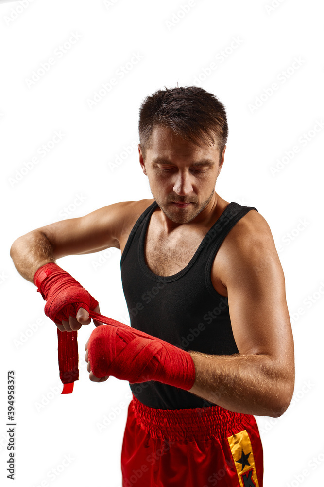 sporty man wraps his hands in red sports bandages before training. Close-up