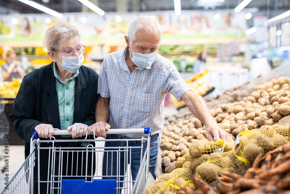 mature couple mature caucasian couple chooses potato in vegetable section of supermarket