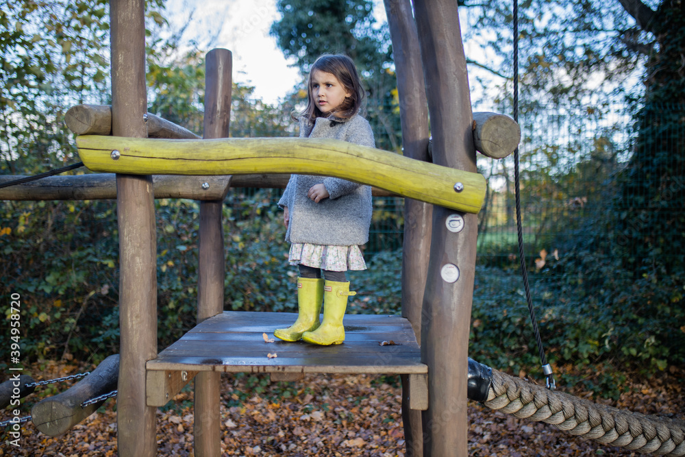 Little girl standing in wooden playground at a park Little girl standing in wooden playground at a park