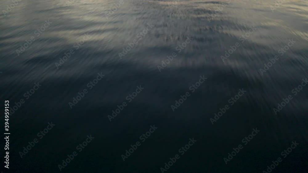 Aerial drone jurassic park opening style shot flying low over water, slowly tilting up to reveal colourful sunset sky to the horizon