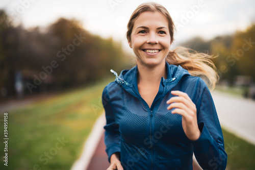 Beautiful adult woman is jogging outdoor on cloudy day in autumn. photo
