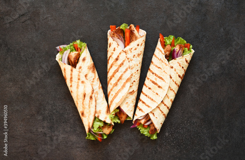 Mexican tortilla grilled wrap with chicken breast and vegetables on concrete background