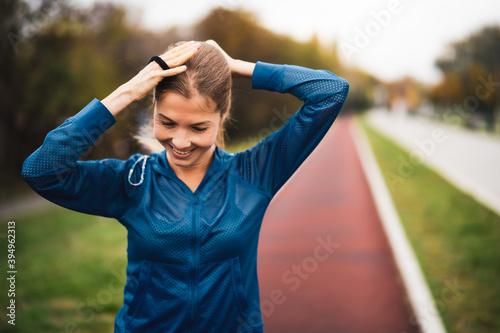 Beautiful adult woman is getting ready for outdoor exercising on cloudy day in autumn.