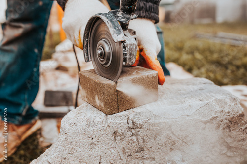 The diamond blade of the grinder quickly and accurately cuts the concrete block - cutting stone tiles for the sidewalk photo