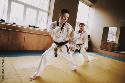 Male karate fighters in kimono practice tricks. 