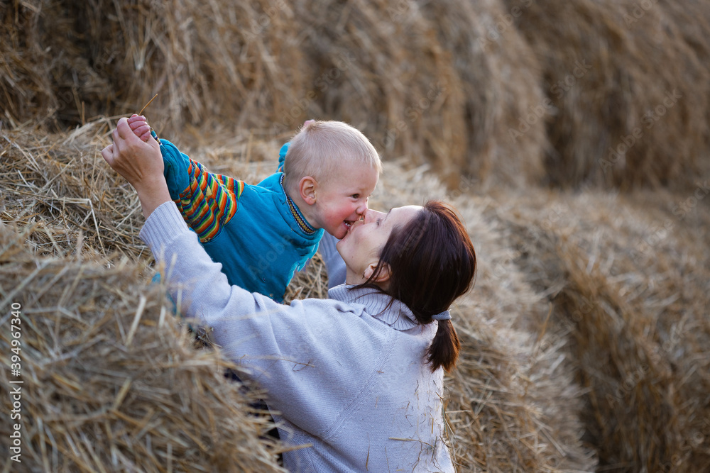 mother with little son in a stack of straw at sunset mother with little son in a stack of straw at sunset