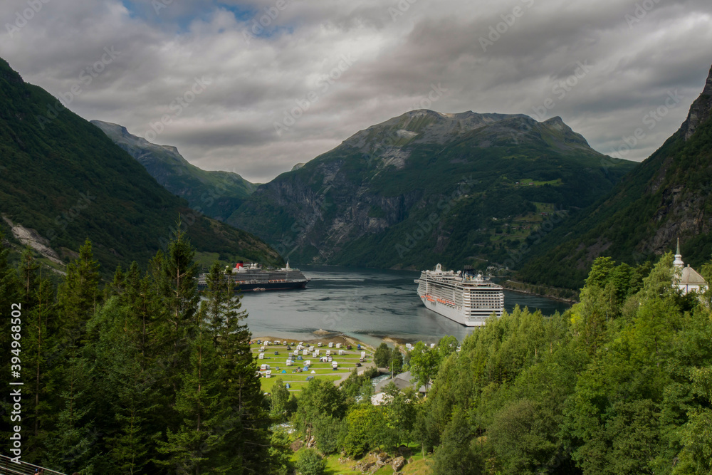 
cruise ship docked at the end of the geiranger fjord, preparing travelers to disembark