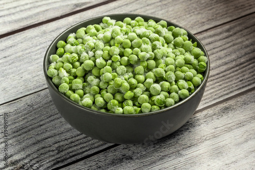 Frozen pea in the bowl on gray wooden table. Horizontal orientation. Close-up.