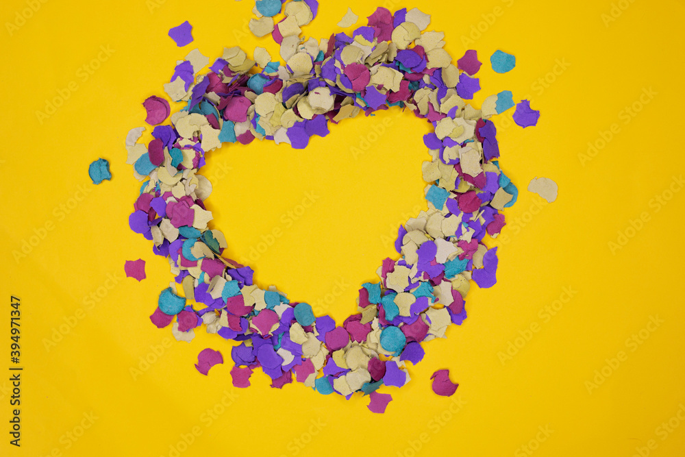 Heart silhouette made with confetti on yellow background Heart silhouette made with confetti on yellow background