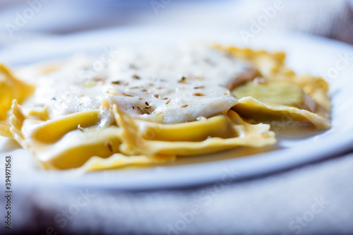 Ravioli fresh pasta dish with cheese sauce and oregano served on a white plate