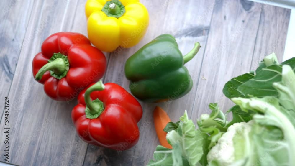 Female hands putting colorful bell peppers and a cauliflower together Female hands putting colorful bell peppers and a cauliflower together