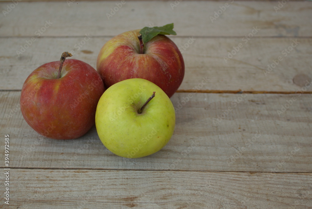 red and one green apple on a wooden table
red and one green apple on a wooden table