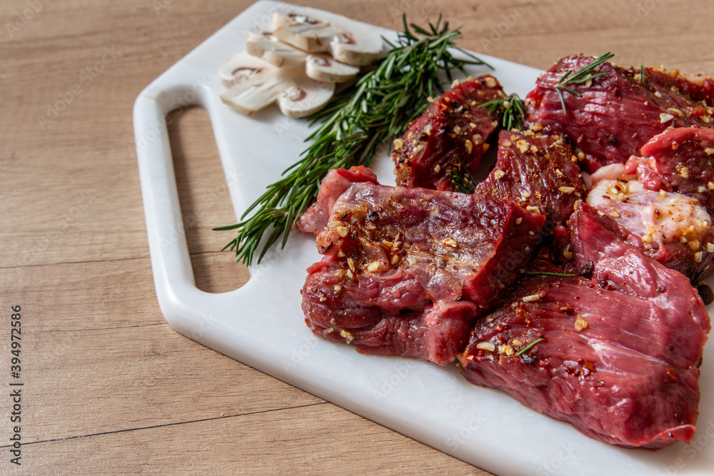 raw lamb chops with rosemary and pepper on marble board. preparing meat. marinated meat. beef. preparing food on kitchen. cooking. beef steak with vegetables