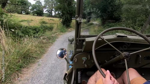 young man driving an antique military car on dirt road