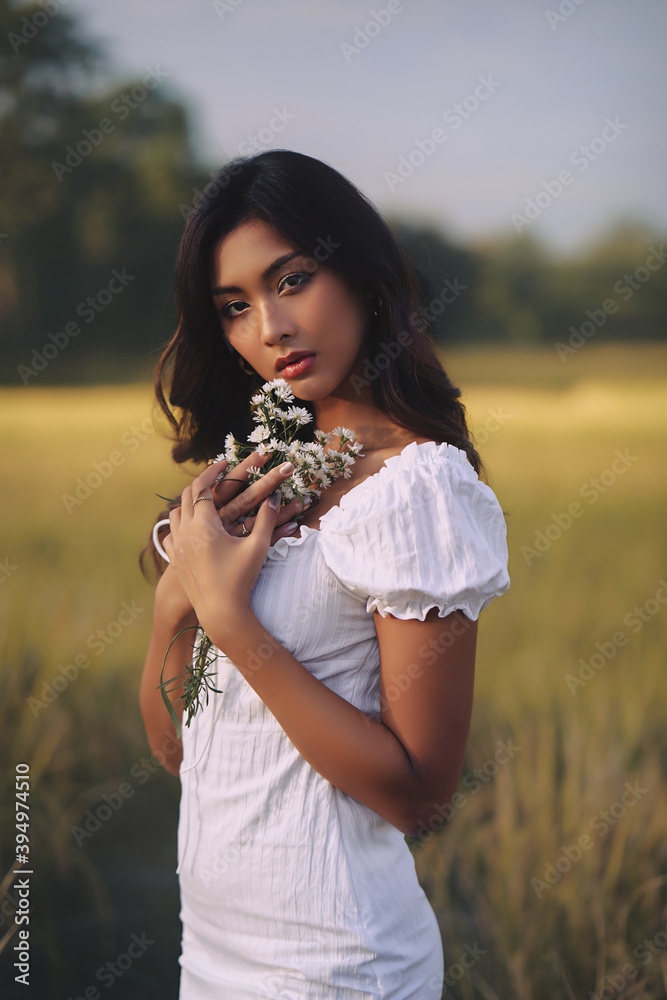 Lifestyle fashion portrait of stylish young asian woman wearing white outfit posing at the field