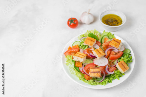 Traditional Middle Eastern vegetarian salad fattoush. Lebanese cuisine recipe. Fresh vegetables, cherry, lettuce, toasted pita bread. White concrete background. Healthy meal. Copy space